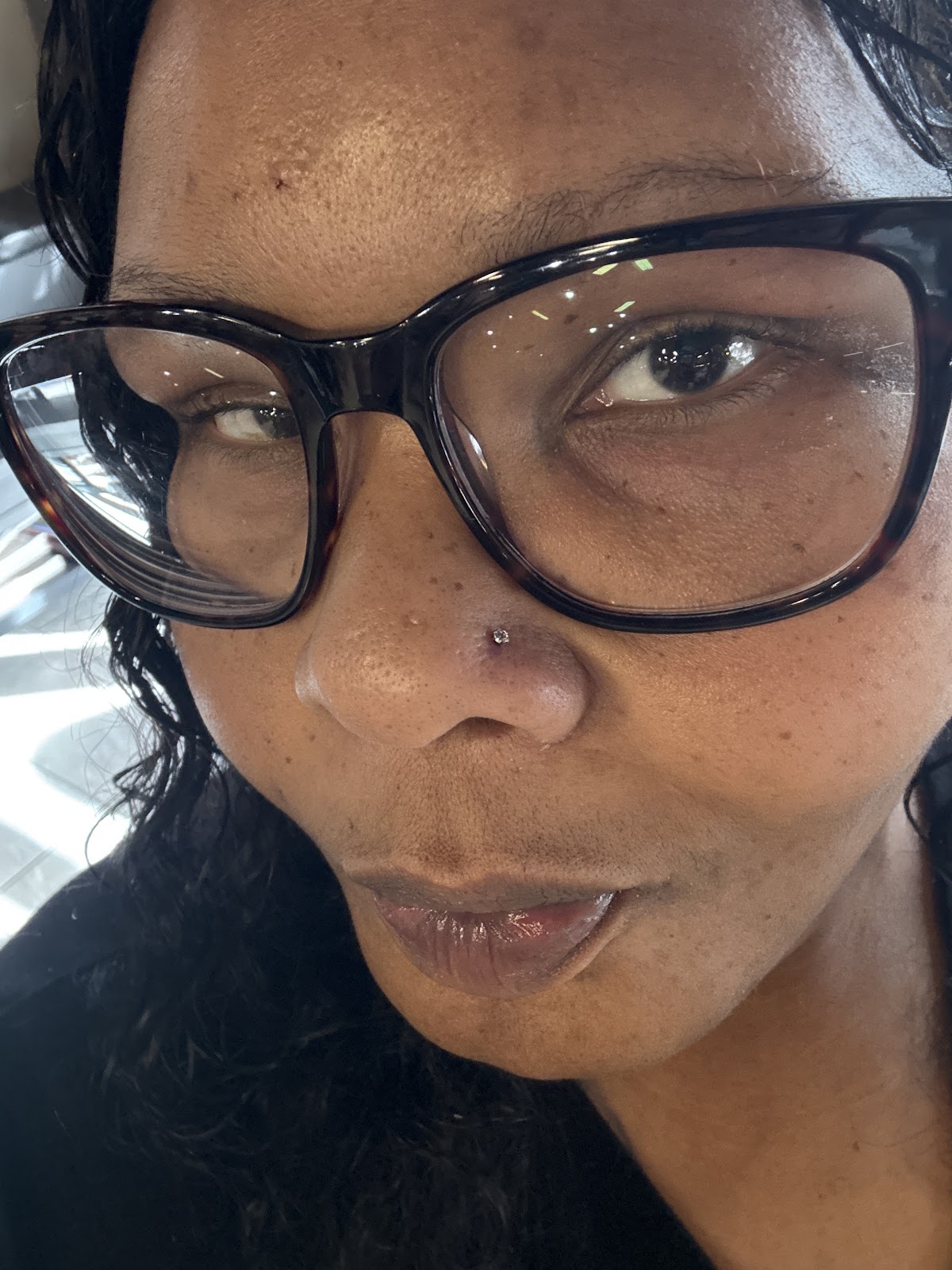 Close-up selfie of a smiling customer wearing a brand-new nose stud